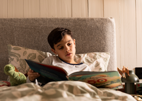 Kid reading a book by himself in bed